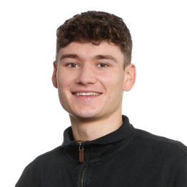 Junger Mann mit dunkeln kurzen Haaren und schwarzem Pullover schaut in die Kamera.