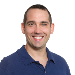 Mann mit dunklen Haaren und in einem dunkeln Hemd schaut in die Kamera.